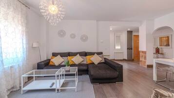 Una sala de estar con sofá, mesa de centro y elementos decorativos en la pared.