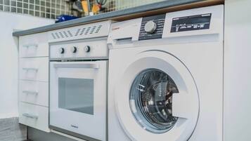 Eine kompakte Waschmaschine und Trockner Kombination mit Bedienfeld und Glastür, eingebaut in einer modernen Küche.