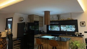Ett modernt kök med en stor köksö, inbyggda vitvaror och ett stort fönster.