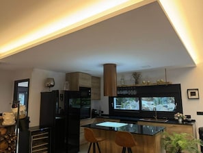 A modern kitchen with a large island, built-in appliances, and a large window. - Luxury chalet with pool in the Sierra de Gredos (La Atalaya)