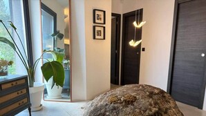 En modern inredning med en stor sten som blickfång, en krukväxt och en minimalistisk dörr.