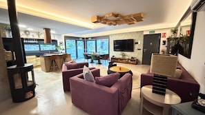 A modern interior with a bar area, seating, and a television. - Luxury chalet with pool in the Sierra de Gredos (La Atalaya)