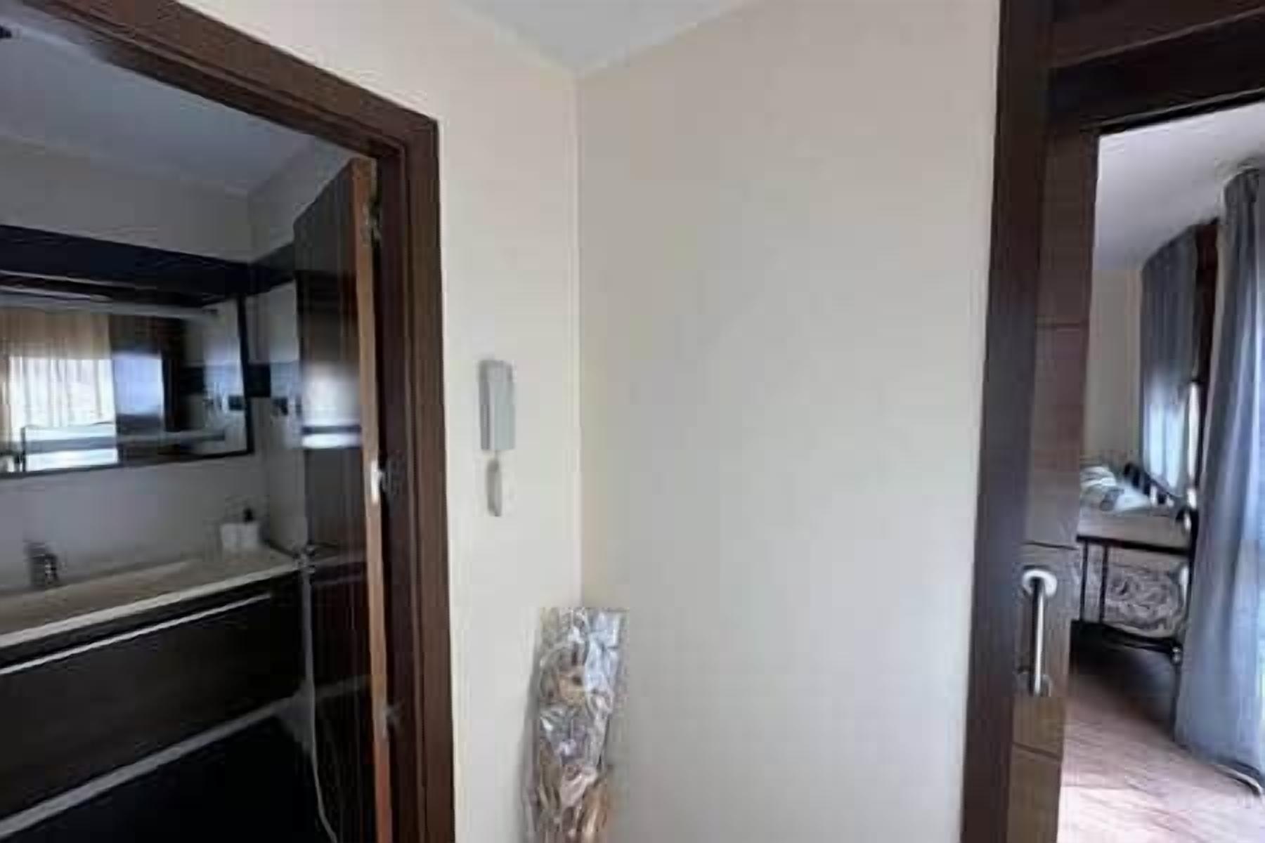 Una habitación de hotel con una puerta de madera, una ventana pequeña y un teléfono en la pared.