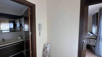 Una habitación de hotel con una puerta de madera, una ventana pequeña y un teléfono en la pared.