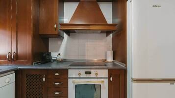 A kitchen with wooden cabinets, a built-in oven, a stove, and a white refrigerator.