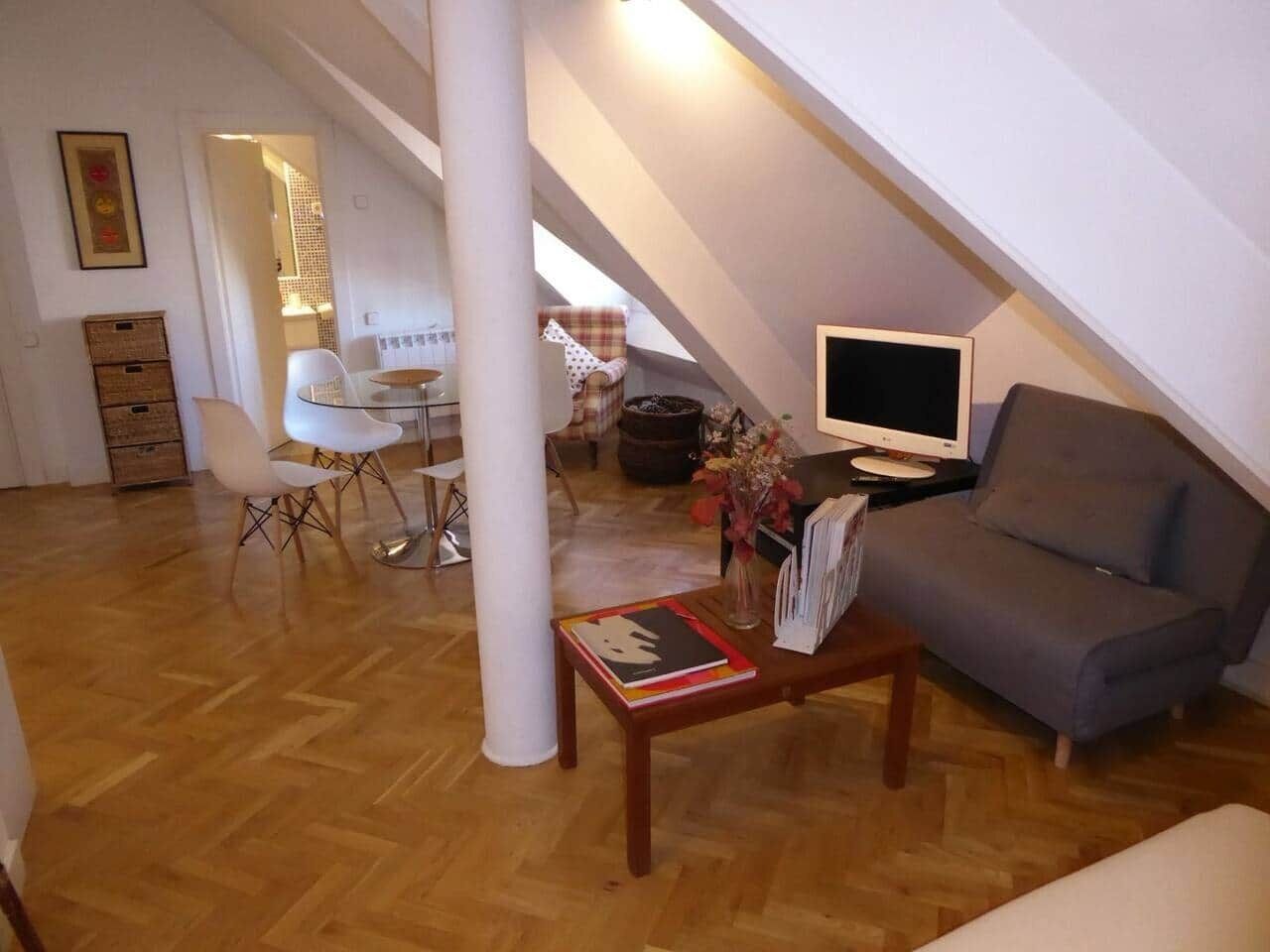Salón con sofá cama, mesa baja y zona de comedor
