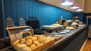 A buffet with bread, pastries, and various dishes.