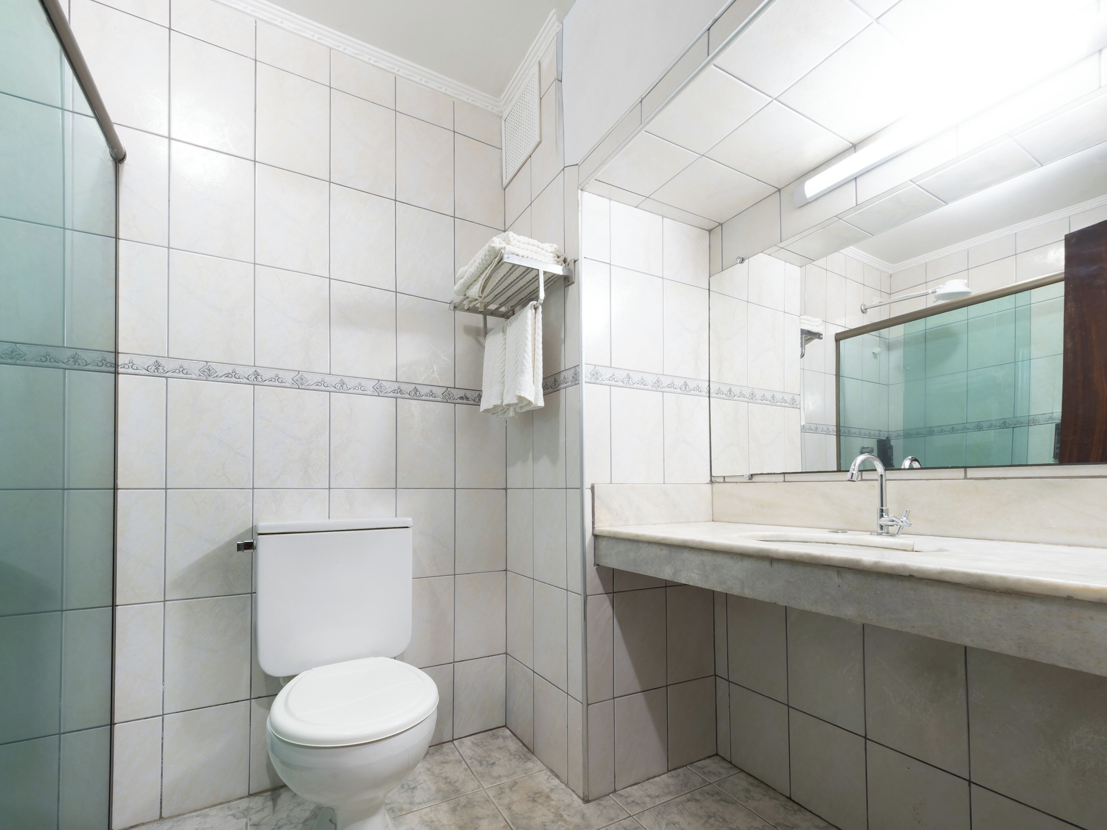 A bathroom with a toilet, a sink, and a mirror.