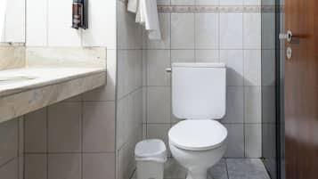 Casa de banho com sanita, lavatório, porta-toalhas e um lixo.