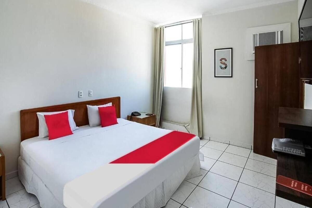 Una camera d'albergo con un letto grande, una scrivania, una sedia, un armadio e una finestra con tende.