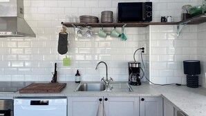 A modern kitchen with white subway tiles, a stainless steel sink, a microwave, and a coffee maker.