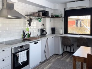A modern kitchen with white cabinetry, a built-in oven, a coffee maker, and a window with a view of the outside. - 4 Star Holiday Home in Uppsala (Uppsala)