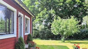 A red house with a well-maintained lawn and potted plants.
