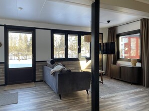 A modern living room with a sofa, a TV, and large windows. - 4 Star Holiday Home in Uppsala (Uppsala)