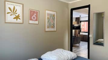 Una habitación de hotel con una cama, colchón azul, colcha estampada y tres cuadros en la pared.