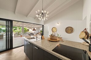 Une cuisine moderne dotée d’un grand îlot central, d’un four encastré et d’un luminaire suspendu.