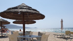 A beachside table with chairs and a table umbrella, overlooking the ocean.