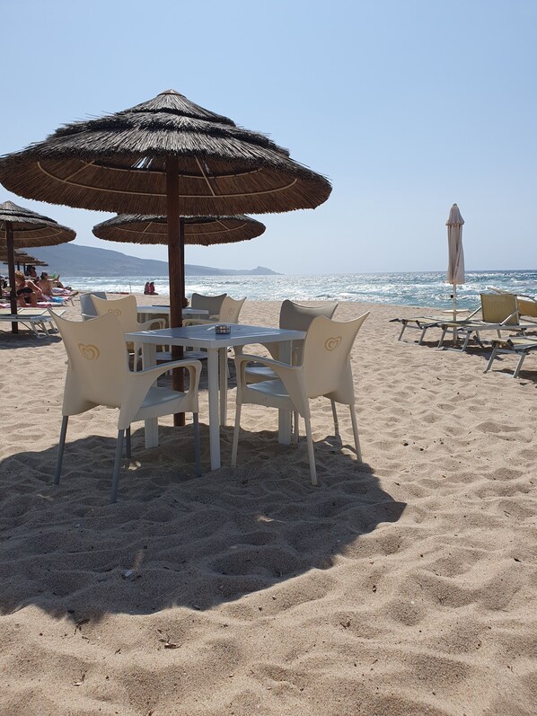 A beachside table with chairs and a table umbrella, overlooking the ocean.