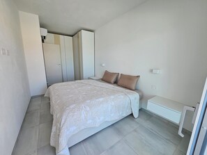 A bedroom with a bed, a bedside table, a wardrobe, and a nightstand.