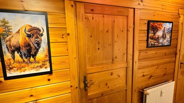 Un interior de madera con dos puertas, una con una pintura de bisonte y otra con un paisaje.