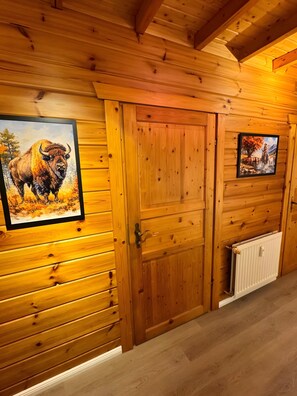 Un intérieur en bois doté de deux portes, l’une ornée d’une peinture représentant un bison et l’autre d’un paysage.