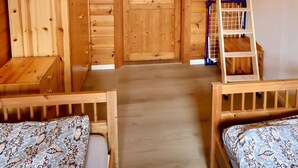 Una cabaña de madera con un dormitorio en el altillo, una escalera y un letrero que dice 'ROOSTER LODGE'.