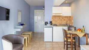Una cucina compatta con zona pranzo, frigorifero, macchina da caffè e schienale piastrellato.