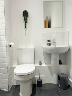 A modern bathroom with a toilet, sink, and mirror. - The Barn in Courtyard, 3 -Bed, Sleeps 5, Long Term Rental Available (Ulverston)