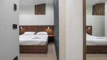 Une chambre d’hôtel avec deux lits, des têtes de lit en bois et des lampes fixées au mur.