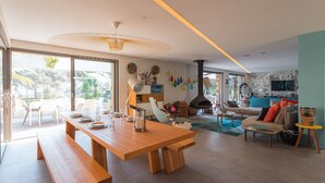 Uma sala de estar moderna com uma mesa de jantar de madeira, um sofá e uma televisão fixada na parede.