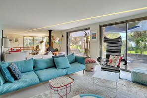 A modern living room with a teal sofa, a white coffee table, and a black and white striped chair.