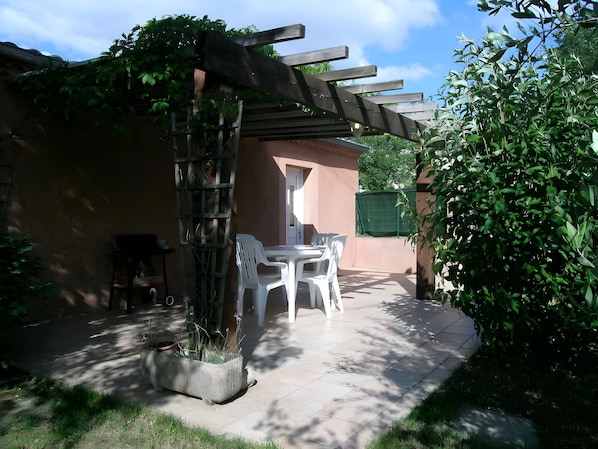A patio with a pergola, a table, and chairs.