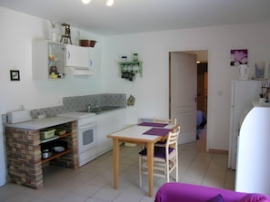 A compact kitchen with a dining area, a brick oven, and a refrigerator.