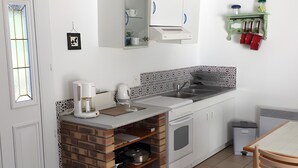 Une cuisine avec des meubles blancs, un mur d’accent en briques, une machine à café, un évier et une table à manger avec des chaises.