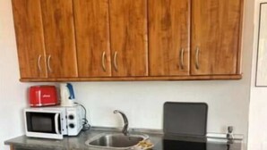 Eine kleine Küche mit Holzausstattung, einer Mikrowelle, einem Toaster und einem Kühlschrank.