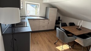 Una cocina moderna con comedor, suelo de madera y una ventana que deja entrar luz natural.