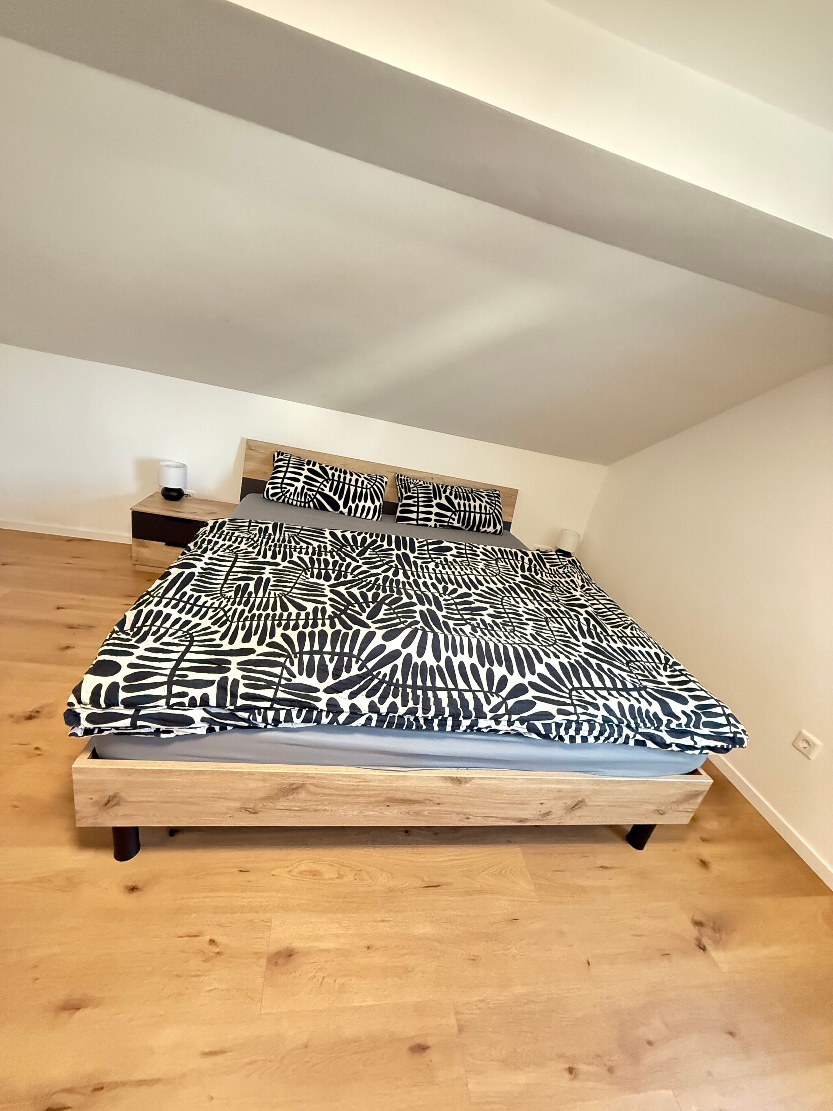 A bedroom with a bed, a nightstand, and a headboard.