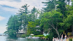 Un muelle con barcos, un espigón y árboles frondosos a lo largo de un lago.