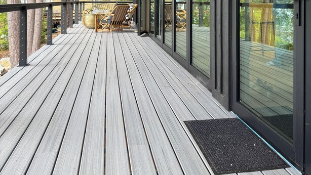 Terraza de madera con techo ventilador, puertas de cristal amplias y mobiliario exterior.