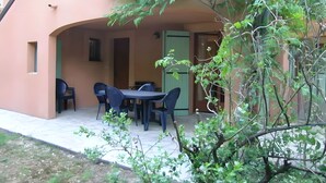 A patio area with a table and chairs, a door, and a small garden. - Gite la Roseraie with Pool (Ruoms)