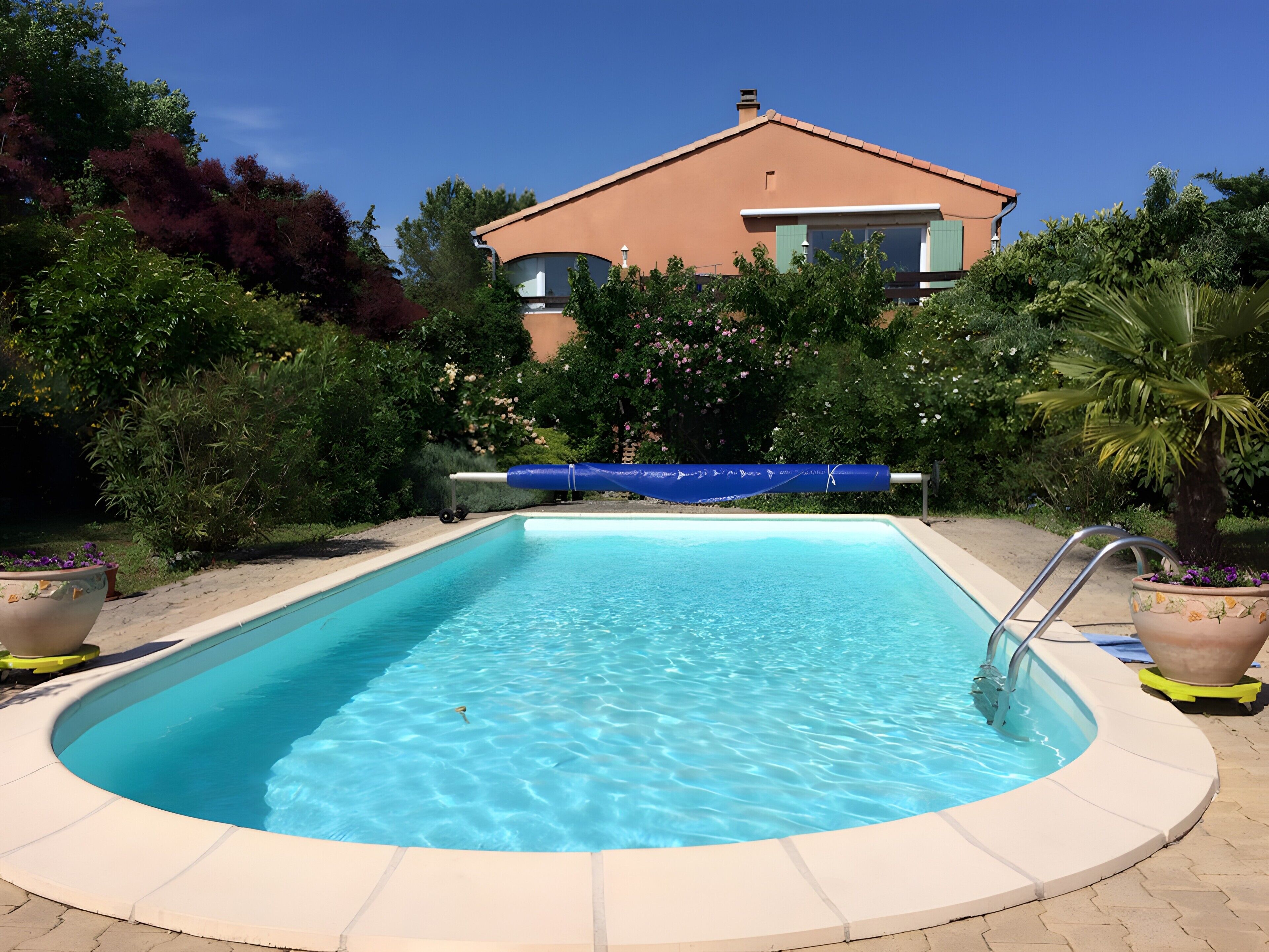 Una piscina rectangular con superficie de agua azul cristalina, rodeada por un deck con baldosas de color claro.