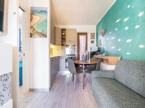 A modern kitchen with wooden cabinets, a dining area with a round table and chairs, and a teal wall with fish decals.
