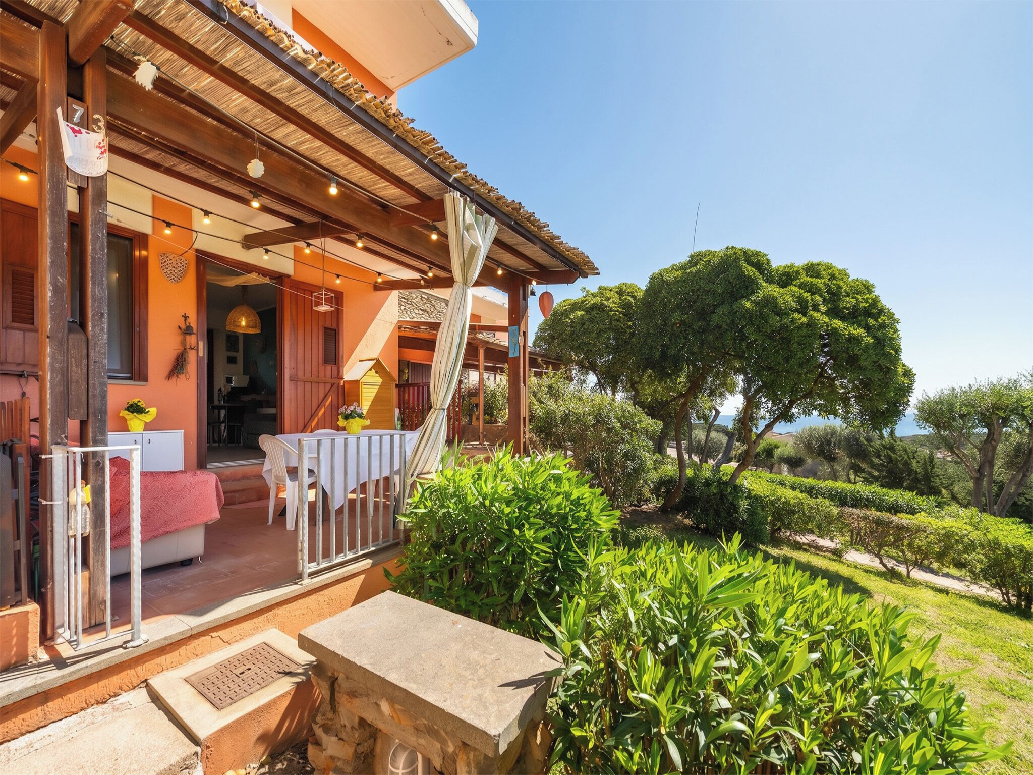 A wooden villa with a covered patio, outdoor seating, and lush greenery.