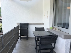 A balcony with a table and chairs, a window, and a small shelf with items. - Joanna vacation apartment with castle view in a central location (Bernkastel-Kues)