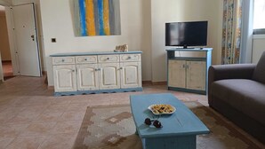 A living room with a sofa, a television, a cabinet, and a painting on the wall. - 1 Bedroom Apartment Praia da Falésia - Comfort, Security, Location of Excellence (Albufeira)