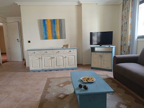 A living room with a sofa, a television, a cabinet, and a painting on the wall.