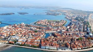 Luftaufnahme einer Küstenstadt mit dicht bebautem Stadtgebiet, einem Yachthafen und einem Strand.
