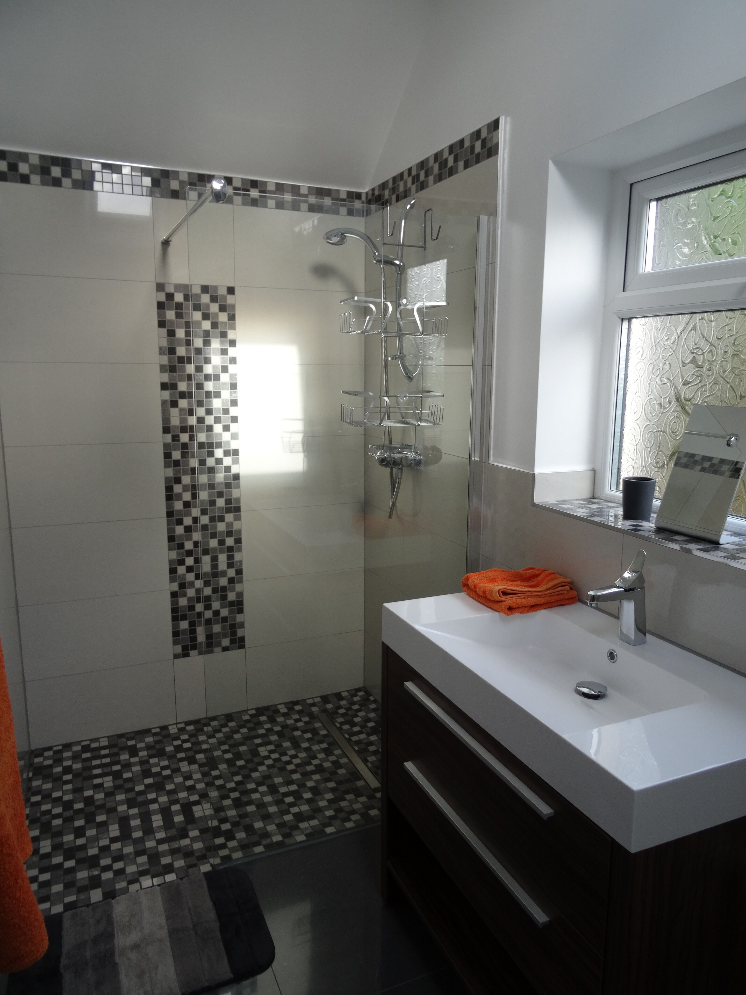 Een moderne badkamer met een douche, een wastafel en een spiegel.