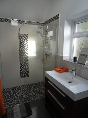 A modern bathroom with a shower, a sink, and a mirror.