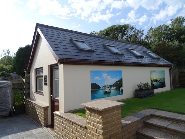 A house with a sloped roof, a brick exterior, and a small garden.